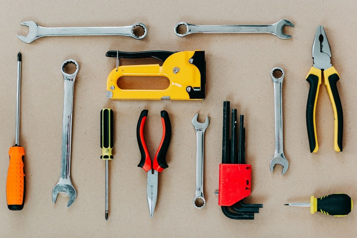 An assortment of plumbing tools and supplies arranged on a wooden table, featuring wrenches, pipes, and connectors.