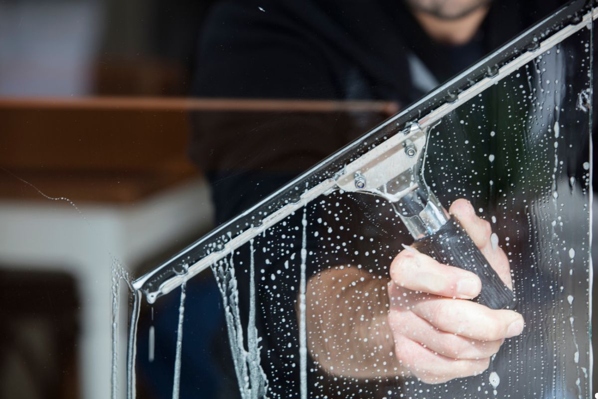 A man using a squeegee to clean a large window, focused on removing streaks for a clear view.