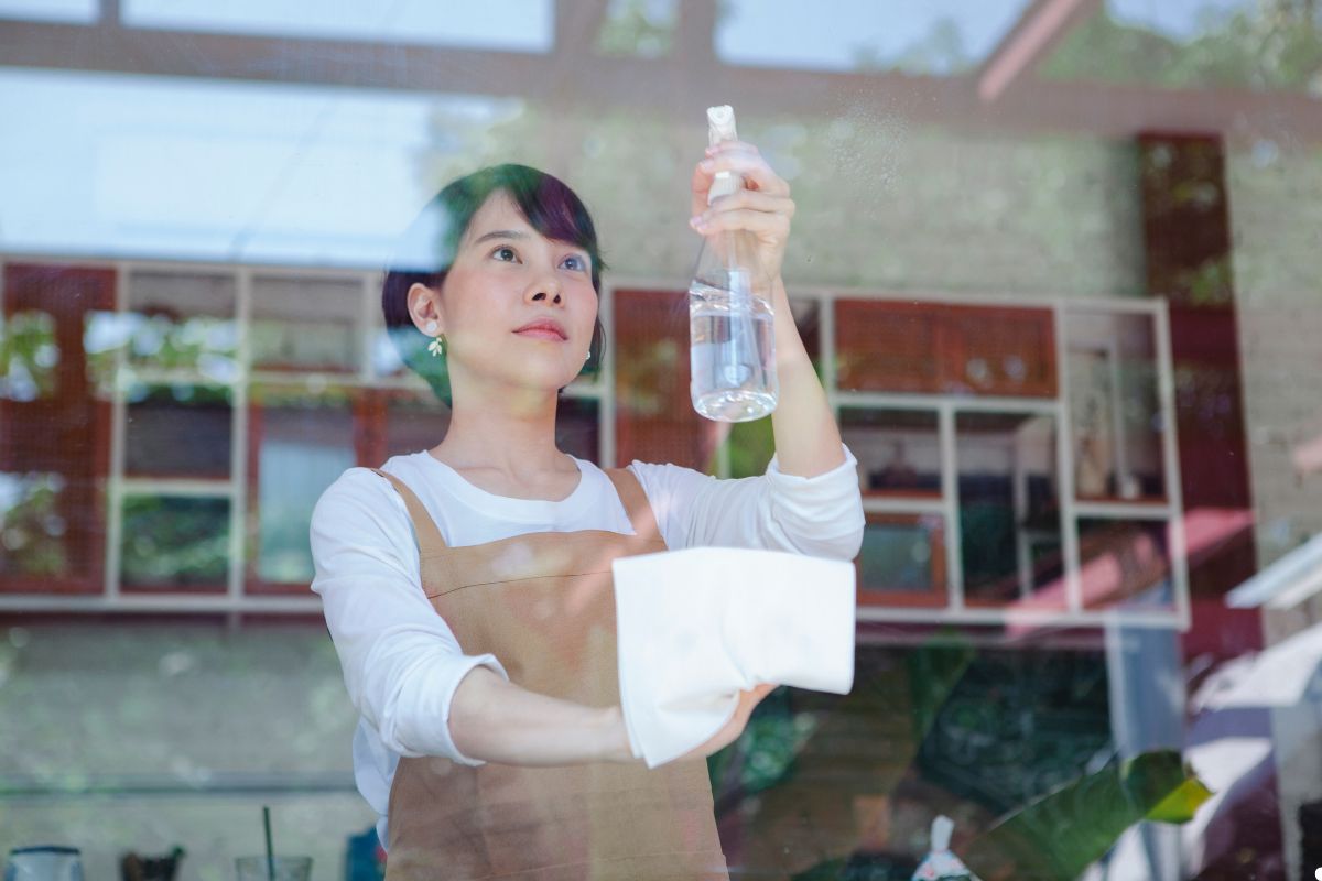 A woman using a cloth to clean a large window, focused on removing smudges for a clear view.