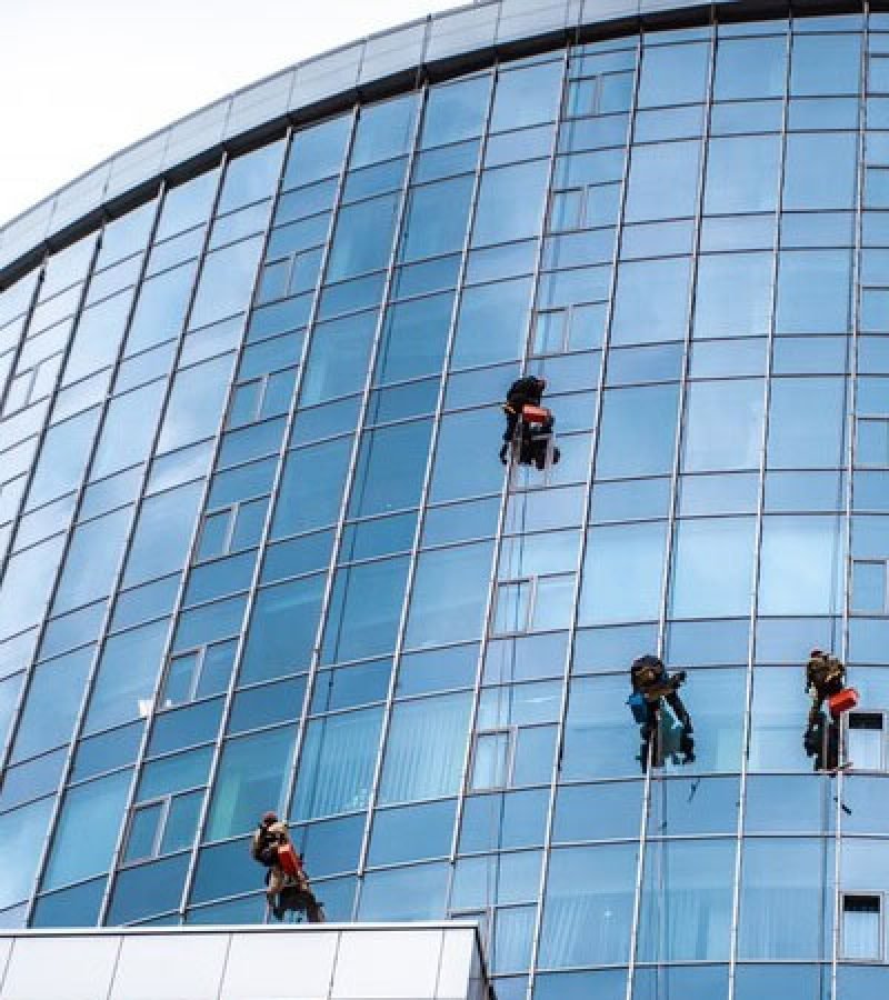 Workers on the windows of a skyscraper, demonstrating a professional commercial window washing service.